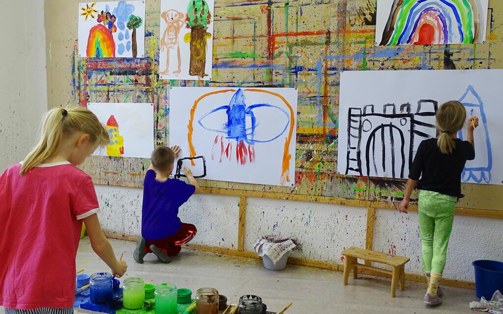 Kinder malen gro&szlig;e Bilder an der Malwand. Im Vordergrund ist die Malorgel zu sehen.