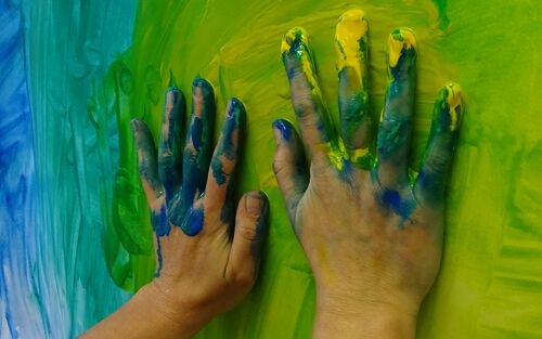 Beim Ausdrucksmalen im Atelier Klang und Farbe darfst du auch mit den Händen malen. Hände auf Papier gelbgrün